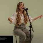 A cantora Gabriela Rocha sorrindo enquanto canta com um microfone em um estúdio