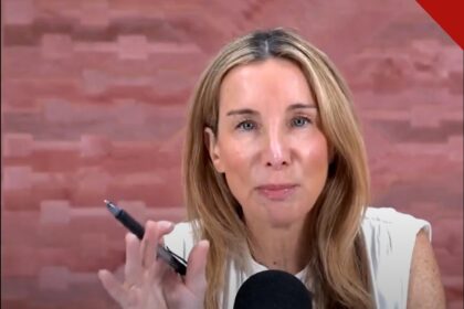 A podcaster Jennifer Welch falando durante a gravação do programa I've Had It, segurando uma caneta diante do microfone