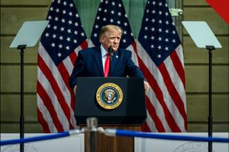 Donald Trump discursa em púlpito presidencial diante de três bandeiras dos Estados Unidos.