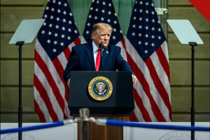 Donald Trump discursa em púlpito presidencial diante de três bandeiras dos Estados Unidos.