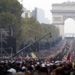 Multidão lota a avenida Champs-Élysées em Paris durante a missa a céu aberto com o Papa Leão XIV, com o Arco do Triunfo ao fundo e bandeiras do Vaticano.