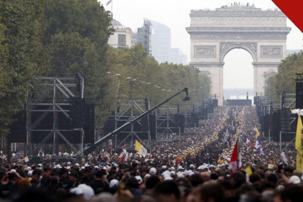 Multidão lota a avenida Champs-Élysées em Paris durante a missa a céu aberto com o Papa Leão XIV, com o Arco do Triunfo ao fundo e bandeiras do Vaticano.