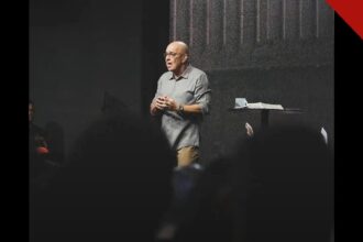 Pastor Ricardo Carvalho, fundador da Igreja Mananciais, pregando no púlpito durante um culto, com a Bíblia aberta ao lado.