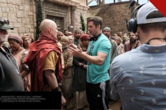 Dallas Jenkins dirige atores caracterizados no set de The Chosen; composição de imagem Hugo Gospel