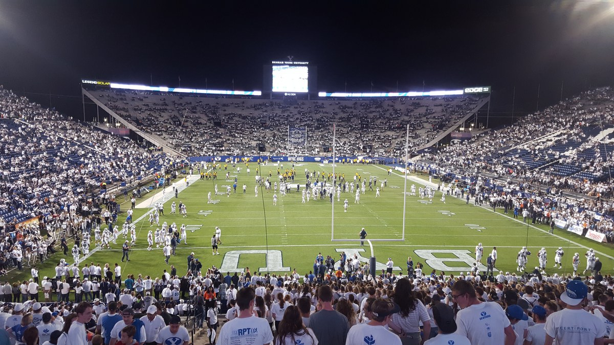 Big 12 multa UCF por cânticos contra mórmons da BYU, e a imagem mostra jogadores de futebol americano da BYU em campo, em partida universitária nos Estados Unidos