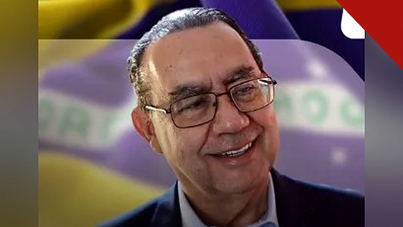 Augusto Cury pede votos para Flávio Bolsonaro: o escritor sorrindo em foto de divulgação, com a bandeira do Brasil ao fundo