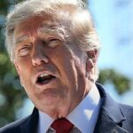 Trump terá de depor no processo contra a BBC: presidente Donald Trump falando ao ar livre, de terno escuro e gravata vermelha