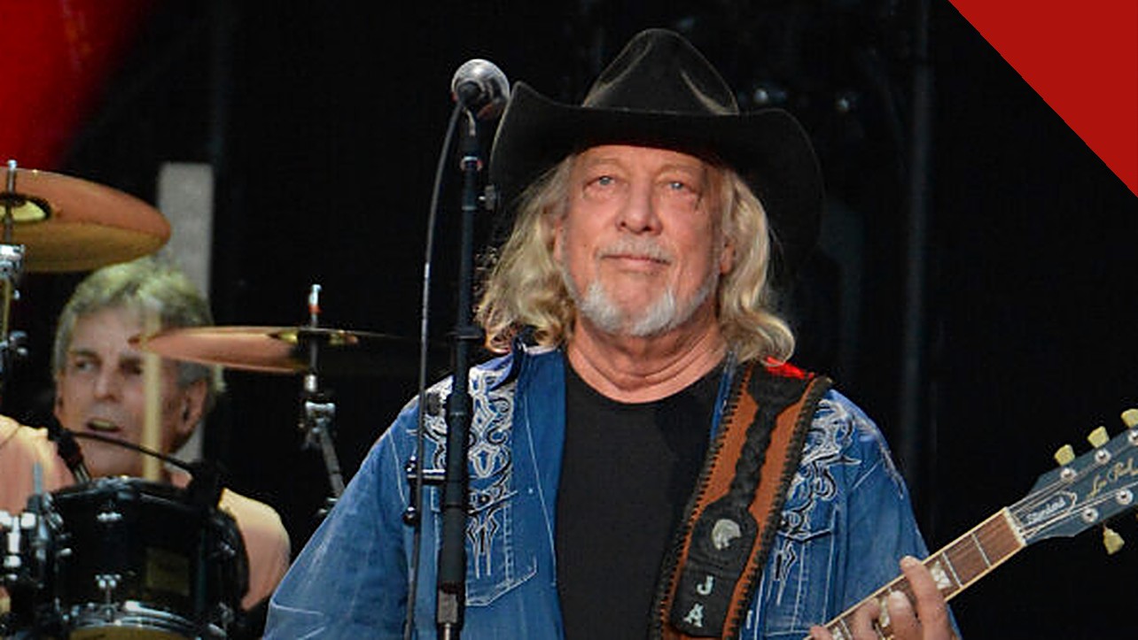 John Anderson morre aos 71 anos: cantor country de chapéu preto e guitarra no palco durante show