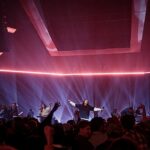 O Hillsong Worship lança novas músicas: culto de louvor com palco iluminado e multidão de braços levantados