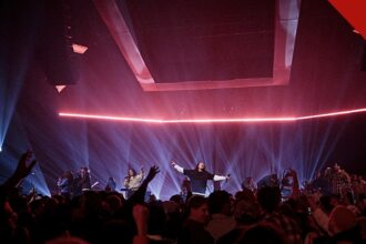 O Hillsong Worship lança novas músicas: culto de louvor com palco iluminado e multidão de braços levantados