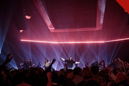 O Hillsong Worship lança novas músicas: culto de louvor com palco iluminado e multidão de braços levantados