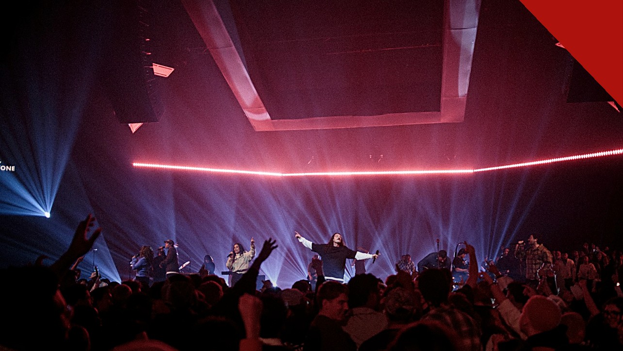 O Hillsong Worship lança novas músicas: culto de louvor com palco iluminado e multidão de braços levantados