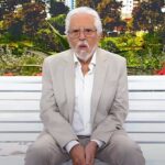 Carlos Alberto de Nóbrega recebe alta: o apresentador de terno claro sentado no banco de A Praça É Nossa, em foto de divulgação