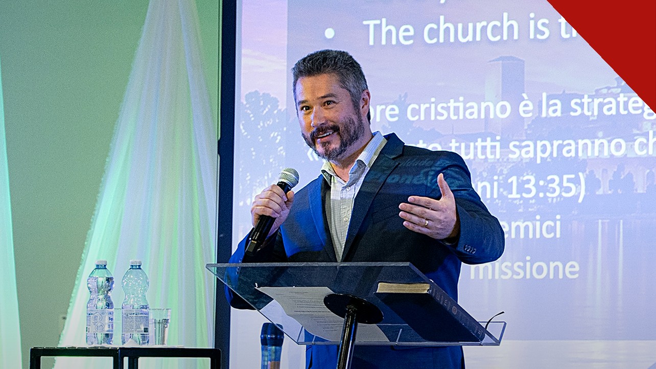 pastor critica fiéis desigrejados: Rick Harrington prega com microfone em conferência cristã na Itália