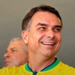 Flávio Bolsonaro sorrindo com a camisa da seleção brasileira, em imagem que ilustra o dia em que Flávio Bolsonaro faz ato em Belo Horizonte