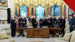 Bispos católicos ao redor do presidente Donald Trump sentado à mesa do Salão Oval, em foto de 22 de outubro que ilustra como o arcebispo defende oração por Trump na Casa Branca após as críticas ao encontro