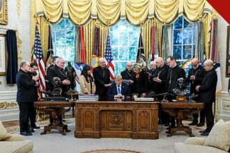 Bispos católicos ao redor do presidente Donald Trump sentado à mesa do Salão Oval, em foto de 22 de outubro que ilustra como o arcebispo defende oração por Trump na Casa Branca após as críticas ao encontro