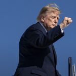 Trump vota antecipado na Flórida: Donald Trump de terno escuro apontando ao desembarcar de aeronave oficial, em foto de outubro de 2026