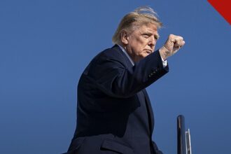 Trump vota antecipado na Flórida: Donald Trump de terno escuro apontando ao desembarcar de aeronave oficial, em foto de outubro de 2026