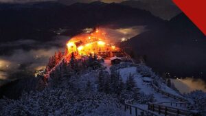 incêndio no Ninho da Águia de Hitler: o edifício do Kehlsteinhaus em chamas durante a noite, no topo nevado da montanha nos Alpes da Baviera