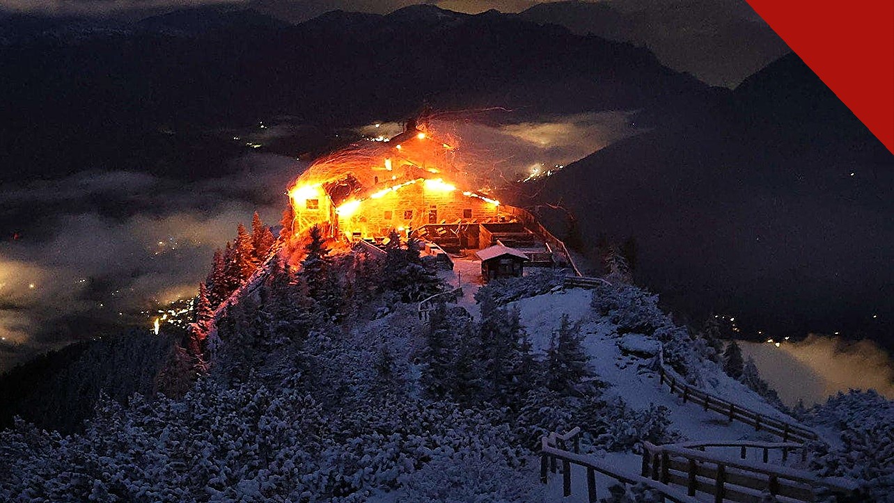 incêndio no Ninho da Águia de Hitler: o edifício do Kehlsteinhaus em chamas durante a noite, no topo nevado da montanha nos Alpes da Baviera