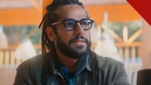 Amaury Lorenzo revela avanço da surdez: o ator como Lucas, personagem da novela Por Você, de dreadlocks e óculos em cena da trama da Globo