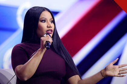 Nicki Minaj em comício com Trump: a rapper falando ao microfone em evento público, de vestido vinho e cabelos longos