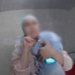 marroquina faz sinal de socorro: mulher de véu claro, com um bebê no colo, faz o gesto de socorro com a mão durante atendimento da Polícia Militar em São Paulo