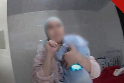 marroquina faz sinal de socorro: mulher de véu claro, com um bebê no colo, faz o gesto de socorro com a mão durante atendimento da Polícia Militar em São Paulo