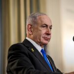 Netanyahu alerta o Irã: Benjamin Netanyahu falando ao microfone em coletiva de imprensa, com a bandeira de Israel ao fundo