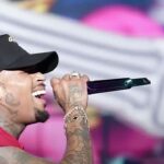 Chris Brown é sentenciado em Londres: cantor Chris Brown cantando em show com boné preto e microfone