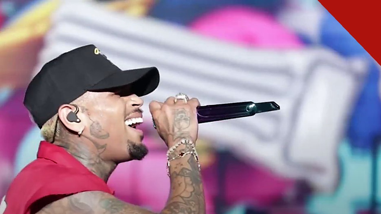 Chris Brown é sentenciado em Londres: cantor Chris Brown cantando em show com boné preto e microfone