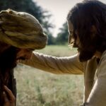 The Chosen sexta temporada: cena da série em que Jesus, interpretado por Jonathan Roumie, toca um leproso em campo aberto