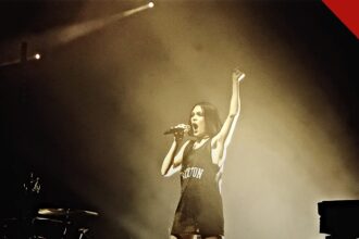 Jessie J mostra recuperação após cirurgia: a cantora Jessie J cantando em show em Londres, com o braço levantado
