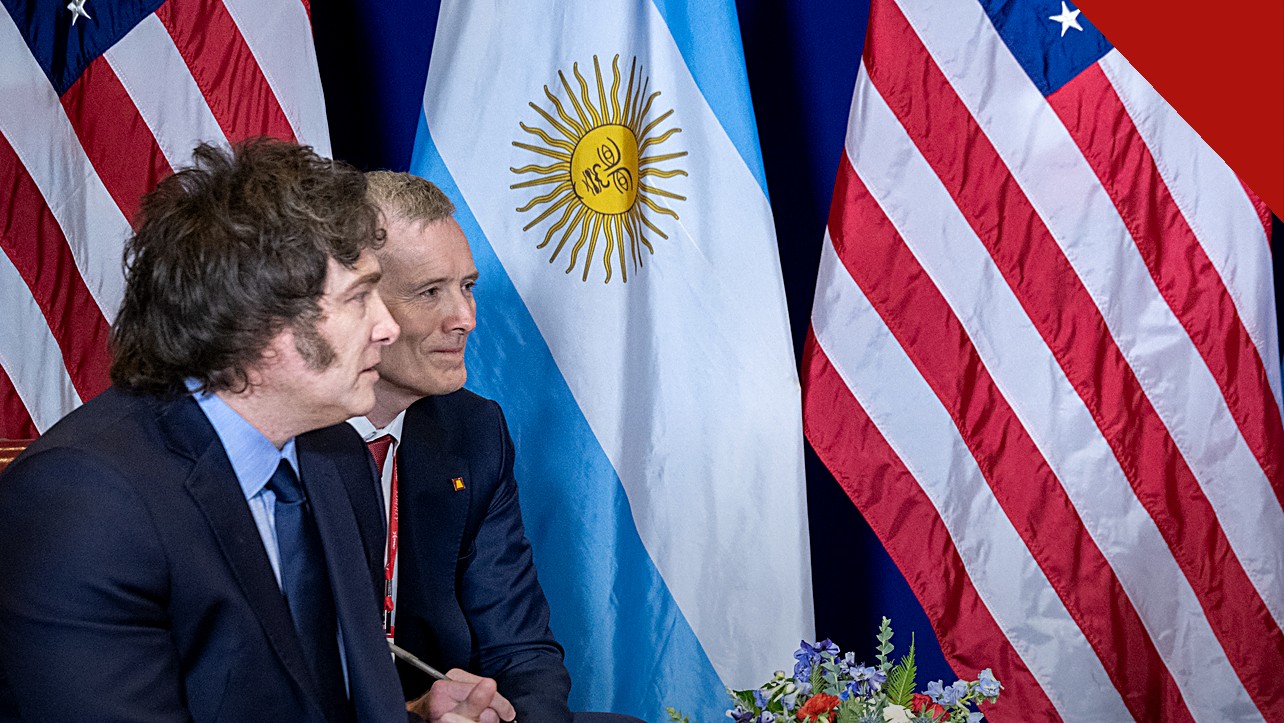 Milei vai à inauguração de igreja evangélica: presidente argentino de perfil, com as bandeiras da Argentina e dos Estados Unidos ao fundo