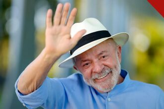 risco-país dispara 26% após reeleição de Lula: presidente sorrindo e acenando, de camisa azul e chapéu claro