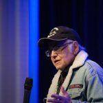 Walter Koenig morre aos 90 anos: ator de boné e jaqueta falando ao microfone em evento com fãs