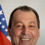 Omar Aziz anuncia pedido de prisão: retrato oficial do senador sorrindo, com a bandeira do Amazonas ao fundo