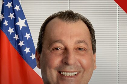 Omar Aziz anuncia pedido de prisão: retrato oficial do senador sorrindo, com a bandeira do Amazonas ao fundo
