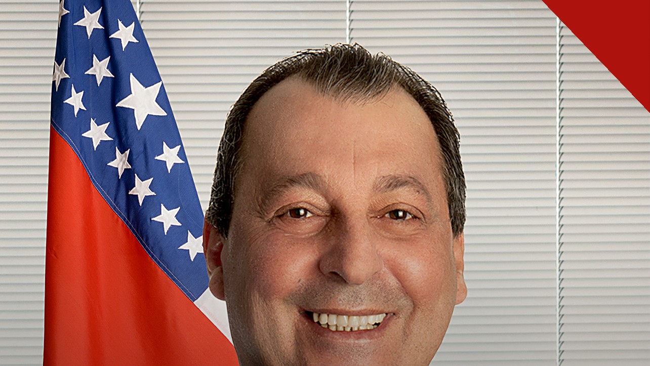 Omar Aziz anuncia pedido de prisão: retrato oficial do senador sorrindo, com a bandeira do Amazonas ao fundo