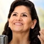 cantora Sara Araújo morre aos 80 anos é o tema de Sara Araújo sorrindo diante de microfone antigo em foto de arquivo