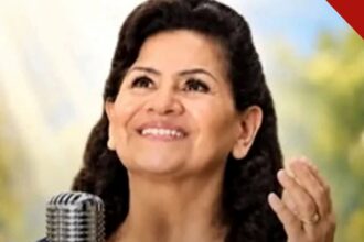 cantora Sara Araújo morre aos 80 anos é o tema de Sara Araújo sorrindo diante de microfone antigo em foto de arquivo
