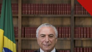 Temer reconhece vitória de Lula é o gesto de Michel Temer, e a imagem mostra o ex presidente em retrato oficial com a bandeira do Brasil ao fundo