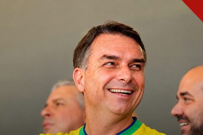 PT pede prisão preventiva de Flávio Bolsonaro ao STF, e a imagem mostra o senador Flávio Bolsonaro sorrindo com a camisa da seleção brasileira