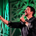 relato de Padre Fábio de Melo volta a repercutir nas redes sociais, e a imagem mostra o Padre Fábio de Melo cantando e apontando em show com luz verde