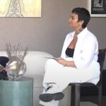 Demi Lovato é hospitalizada após reação alérgica e recebe alta, e a imagem mostra a cantora Demi Lovato sentada de roupa branca em entrevista