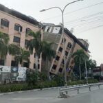 cristãos em Mianmar um ano após terremotos de magnitude 7,7, e a imagem mostra um prédio inclinado e danificado em Mandalay, em Mianmar, após o terremoto de 2025