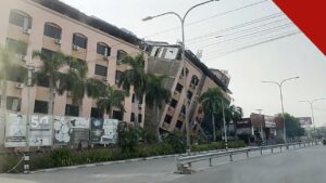 cristãos em Mianmar um ano após terremotos de magnitude 7,7, e a imagem mostra um prédio inclinado e danificado em Mandalay, em Mianmar, após o terremoto de 2025