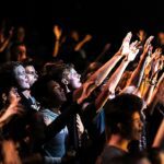 jovens adultos frequentam cultos mais que os pais, e a imagem mostra jovens em um culto nos Estados Unidos durante um momento de adoração