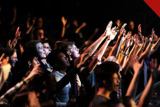 jovens adultos frequentam cultos mais que os pais, e a imagem mostra jovens em um culto nos Estados Unidos durante um momento de adoração
